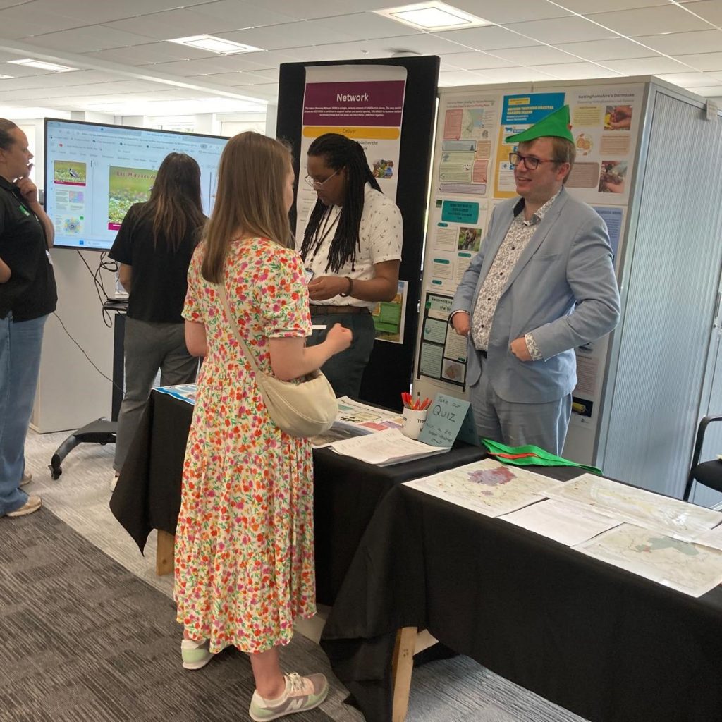 People talking at a display stand at a conference.